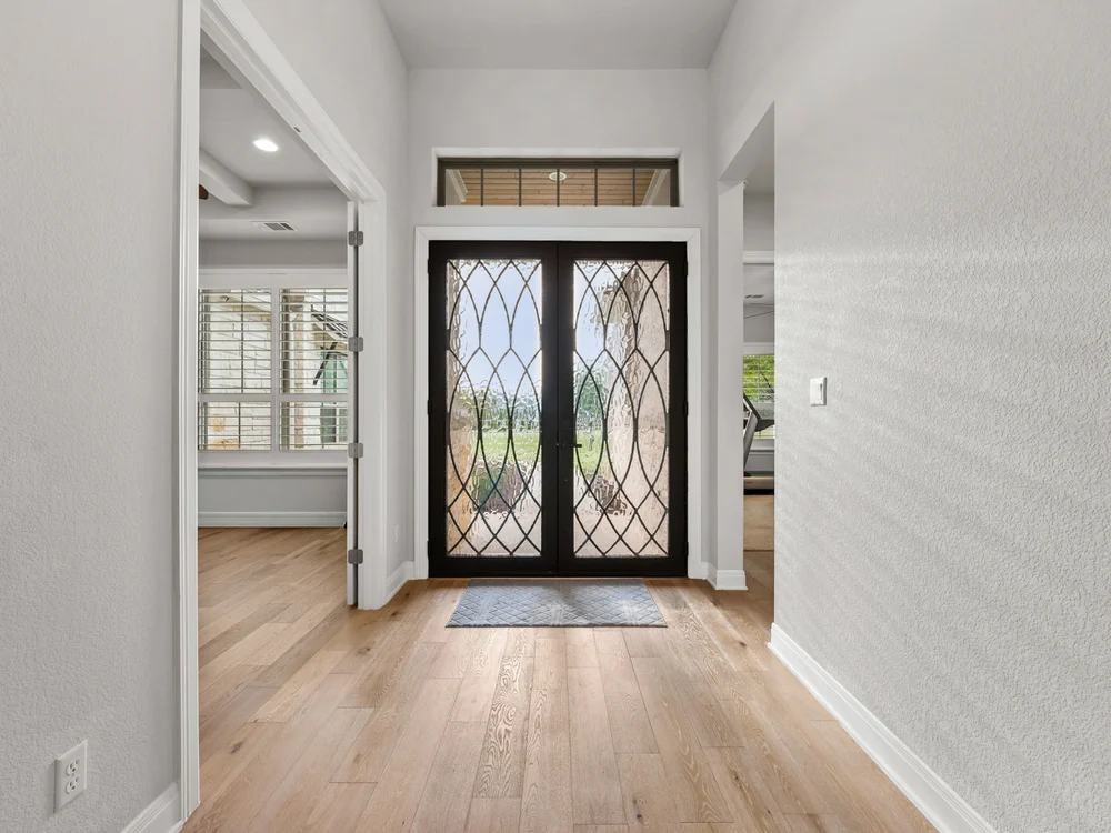 Bright entryway with wood flooring and decorative glass double front doors