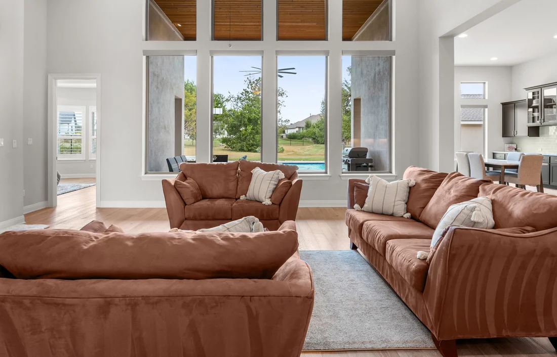 Living room with tall windows overlooking the covered porch and private pool